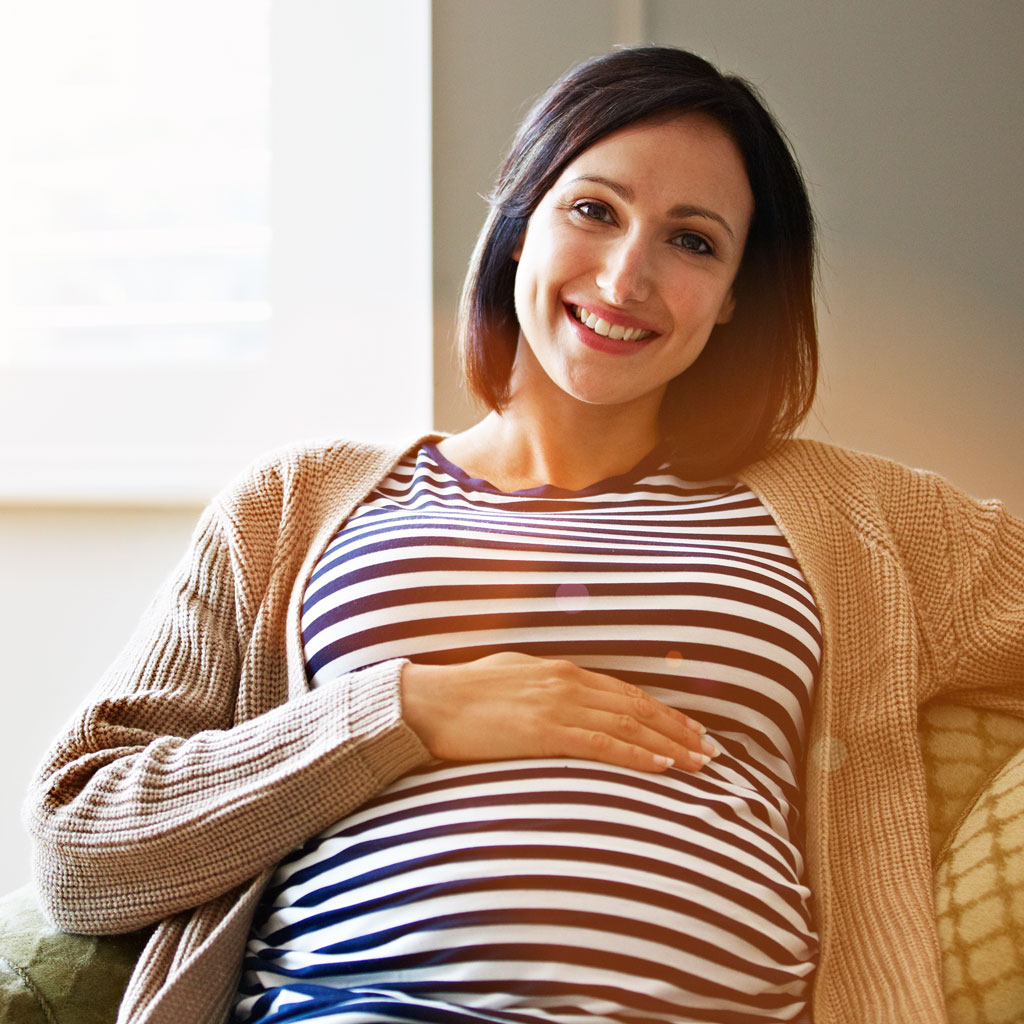 Smiling pregnant woman on couch
