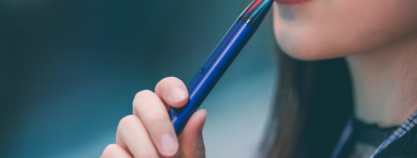 Young woman about to use a blue vaping device