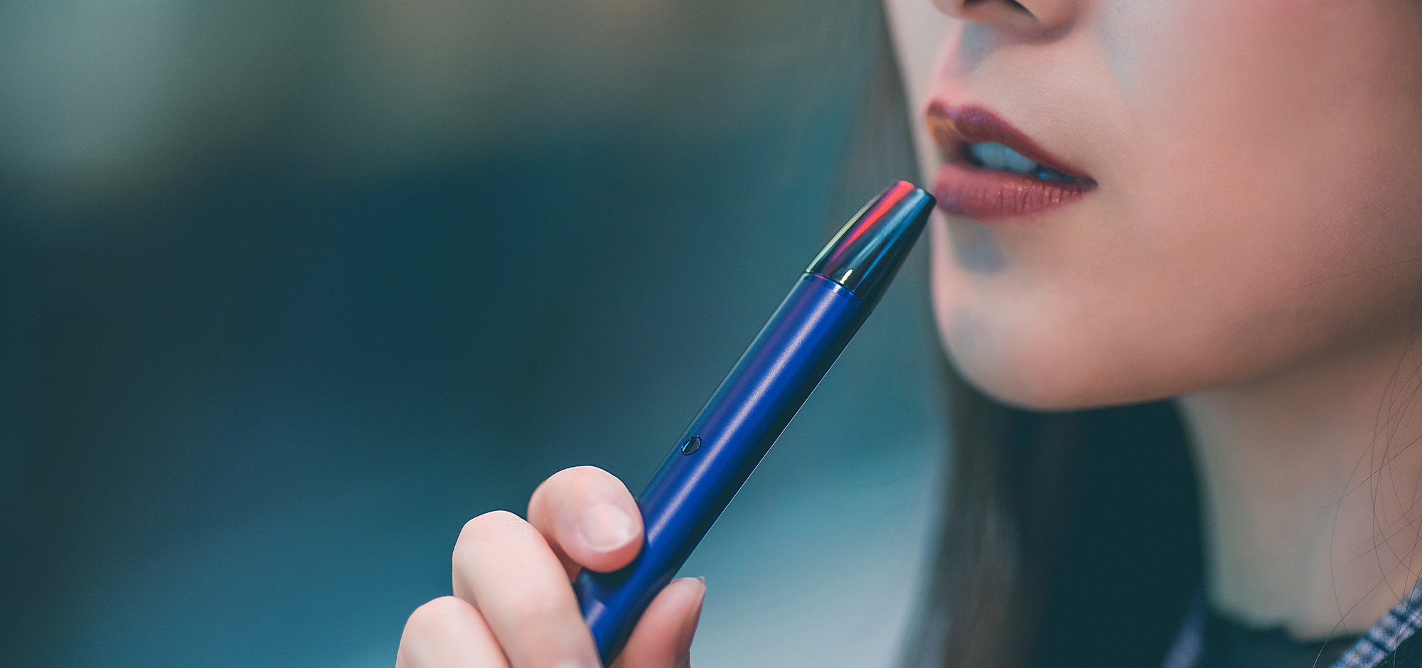 Young woman about to use a blue vaping device